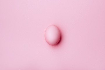 Pink egg on pink background - top view. copy space.