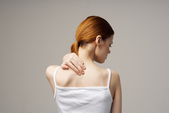 a woman in a white T-shirt hurts her back