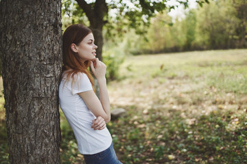 woman in white t-shirt leaned on a tree