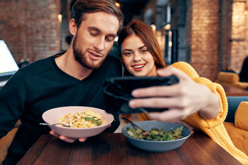young couple taking selfie on a smartphone sitting in a cafe