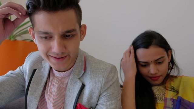 Young Indian couple vain and snob settle their hair using the screens of their cellphone 