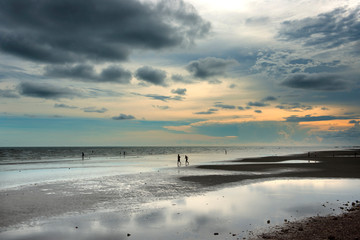 Man and women running on tropical beach at sunset