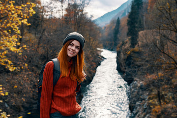 woman traveler smiling on the background of the river in the nature autumn forest