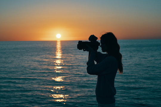 sunset at sea woman photographer with camera