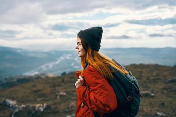 woman in a hat with a backpack in the mountains
