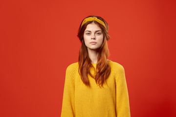 serious woman in yellow sweater over orange background. fashion