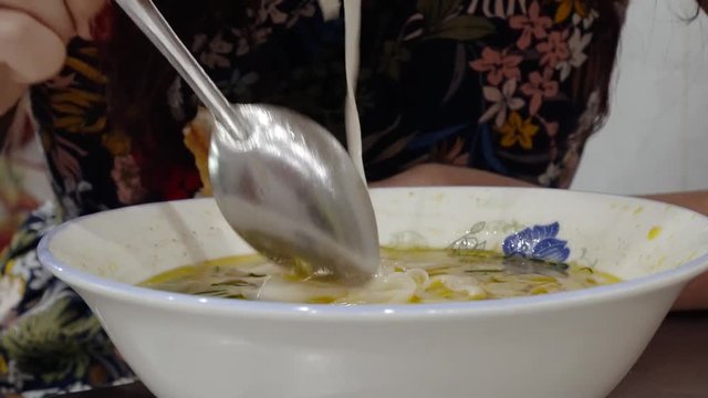 Asian street cafe. Vietnamese noodle soup, pho soup. A woman, a cafe visitor, eats soup.