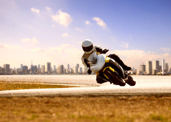 man wearing safety suit riding sport racing motorcycle on sharp curve highway