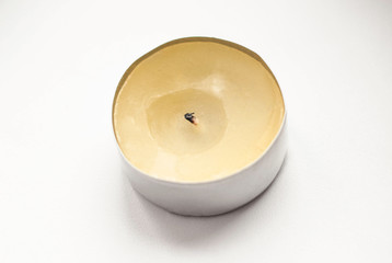 Round candle with black wick on white background.