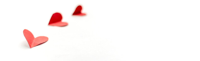three red paper hearts isolated on white background, close up focused on nearest heart long banner
