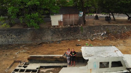 aerial view of young couple in the old boat aground, tropical island of Bali, Indonesia.