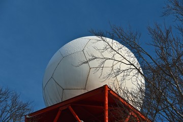 The white dome of the radar on the tower in the woods.