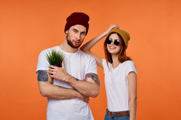 young couple in white t-shirt hats on orange background