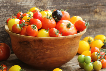Wooden bowl with fresh vine ripened heirloom tomatoes from farmers market