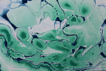 Close up of a swirly textured background in greens and blues.