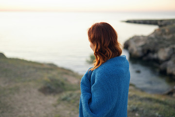woman in a blanket is looking to the sea