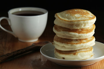 A stack of freshly backed pancakes and a cup of coffee