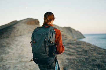 young woman with a large hiking backpack on nature trip