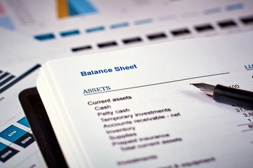 balance sheet and pen on the background of financial documents, close-up