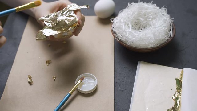 Young woman paints gold easter egg