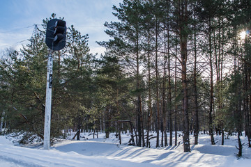 Railway semaphore in winter green pine forest. Blue sky and clouds. Morning in the winter forest....