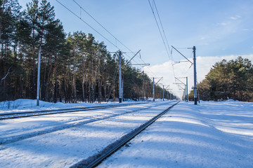 Snowy landscape with railway. Winter forest and blue sky. Beautiful morning in the forest.