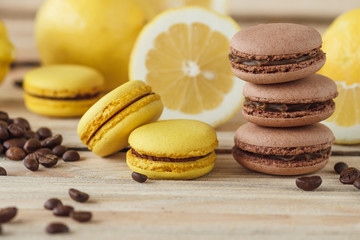 Yellow and brown french macarons with lemons and coffee beans on the wooden board