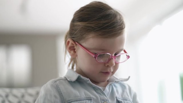 Close up of adorable young girl playing and wearing eyeglasses