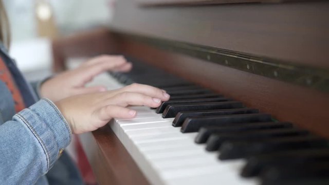 Close up of young child's hands playing the piano