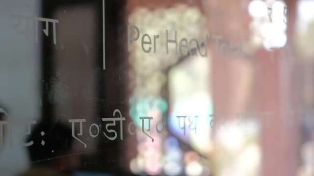 View of the ticket counter at at Tomb of Itimad ud Daulah ka Maqbara, a Mughal mausoleum in Agra, India, reflection ticket rupees beyond glass out of focus bokeh