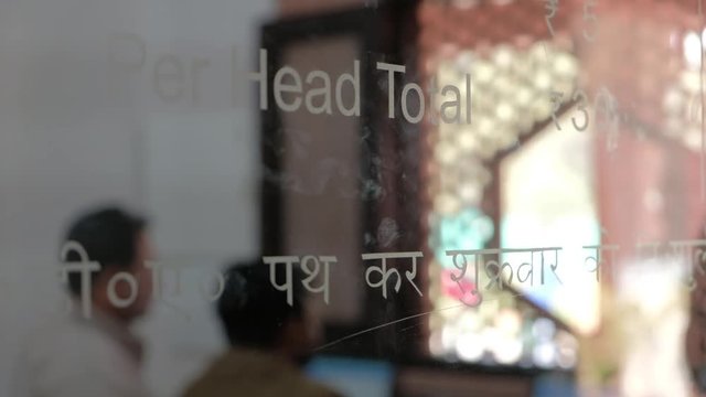 View of the ticket counter at at Tomb of Itimad ud Daulah ka Maqbara, a Mughal mausoleum in Agra, India, reflection ticket rupees beyond glass out of focus bokeh
