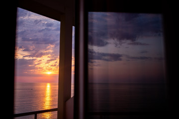 Beautiful sunset above the sea or the ocean, tropical resort. View from the hotel window