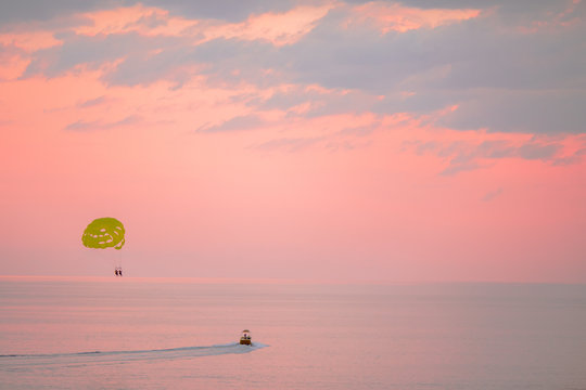 Yellow parasail wing pulled by a boat on beautiful pink sunset