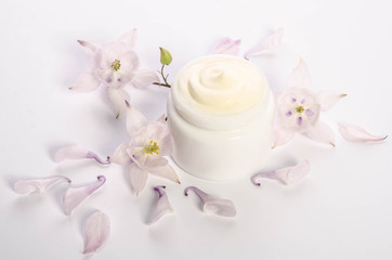 Obraz na płótnie Canvas Cute flowers and petals and a jar of natural body cream isolated on white background
