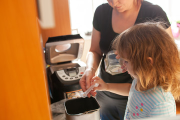 Mother and daughter making bread together at home kitchen