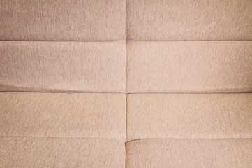 A close-up of a fragment of an expensive beige textile sofa in the room