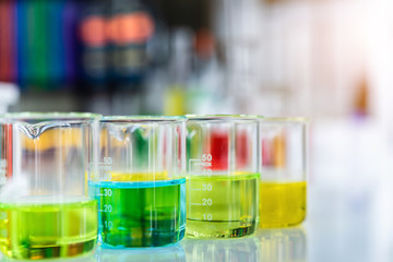 Lab glassware containing chemical liquid with laboratory background, science research and development concept 