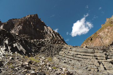 Wide angle view of a rocky slope on a sunny summer day. Structural hexagonal cliffs in the North Caucasus