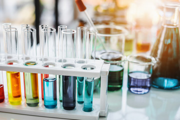 Lab glassware containing chemical liquid with laboratory background, science research and development concept 