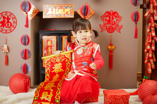 Chinese baby girl  traditional dressing up with a Gong Xi Fa Cha scrolls means wishing you enlarge your wealth