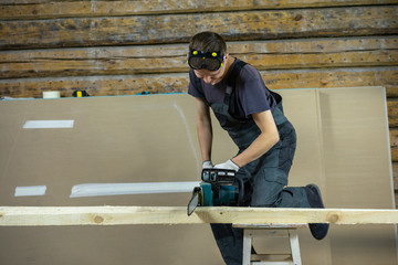The builder saws wood electric saw. He likes this job.