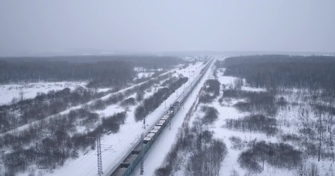 Freight train carries with coal an electric locomotive by Trans Siberian railway in winter cloudy frozen day - Aerial View