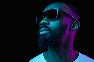 The retro wave or synth wave portrait of a young happy smiling african man in sunglasses at studio....