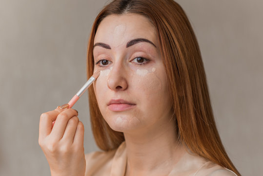 Woman with problem skin prone to rashes and acne, acne scars put on make up concealer and foundation , concept of healthy skin, dermatology and cosmetology  