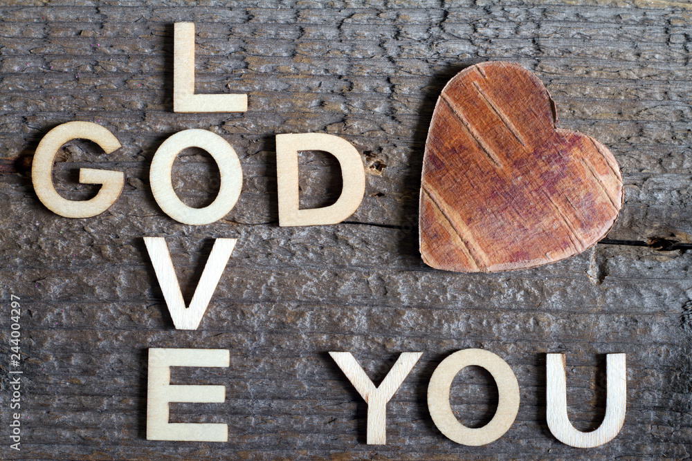 Wall mural God is love letters with cross and heart religion concept on wooden background 