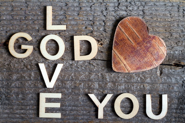 God is love letters with cross and heart religion concept on wooden background 