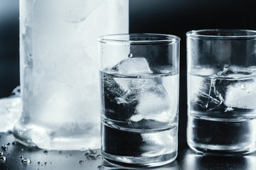 Cold vodka in shot glasses on a black background.