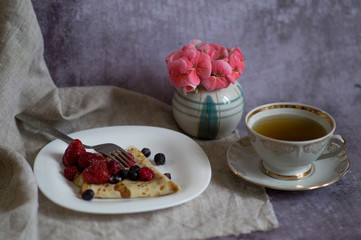 Russian carnival. The traditional dish of the Slavs thin pancakes at Shrovetide. Pancakes composed of a triangle with strawberries, raspberries and currants and a cup of tea