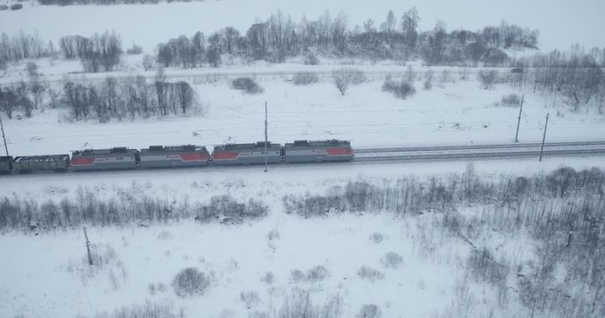Freight train carries with coal an electric locomotive by Trans Siberian railway in winter cloudy frozen day - Aerial View