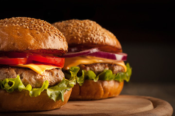 Home made hamburger with beef, onion, tomato, lettuce and cheese. Fresh burger close up on wooden rustic table with potato fries, beer and chips. Cheeseburger.